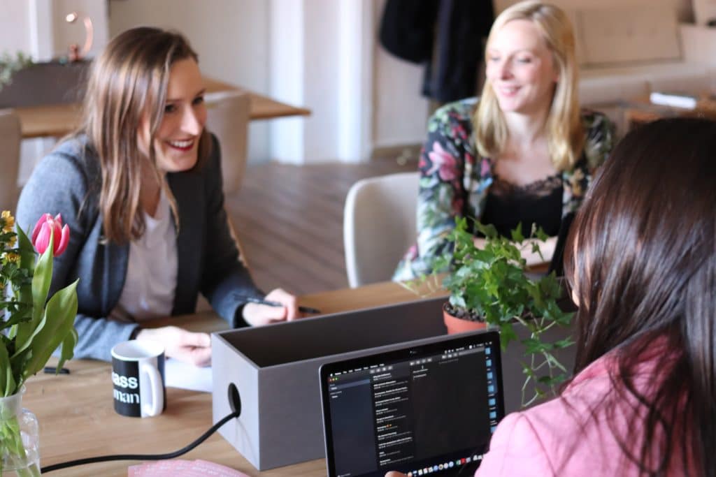 Gutes Arbeitsklima: Frauen sitzen gemeinsam am Schreibtisch